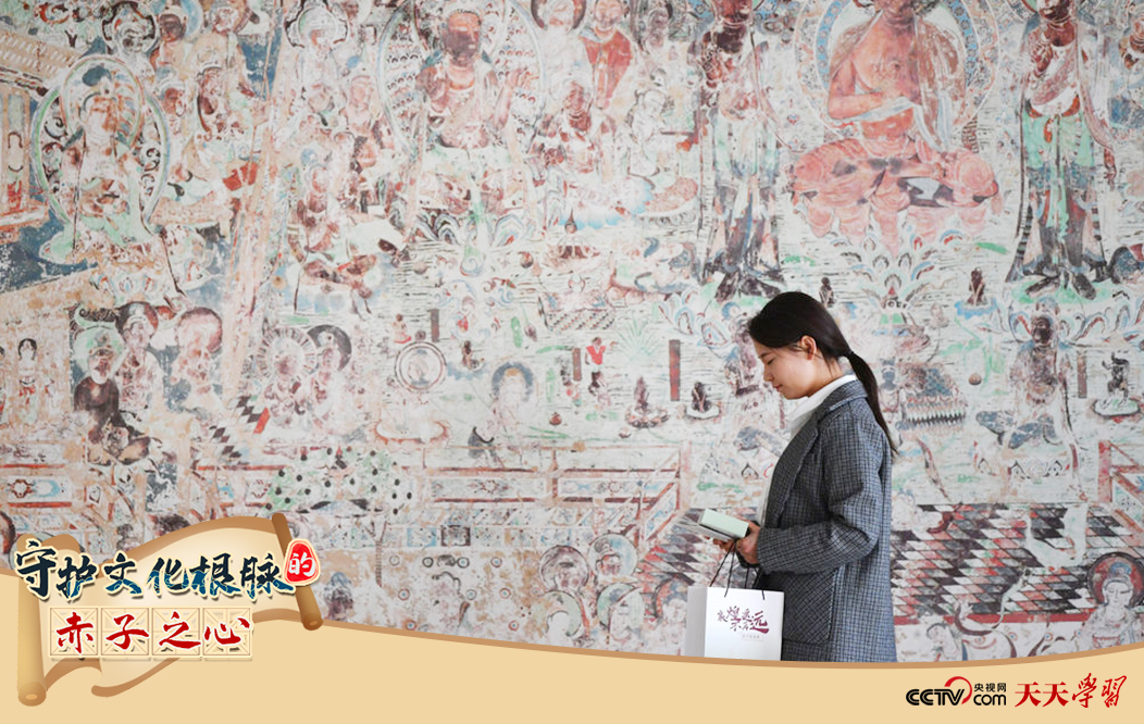2023年4月25日，敦煌研究院文物數(shù)字化保護團隊創(chuàng)意營銷人員廖雪婷從一幅高保真復(fù)制壁畫前走過。